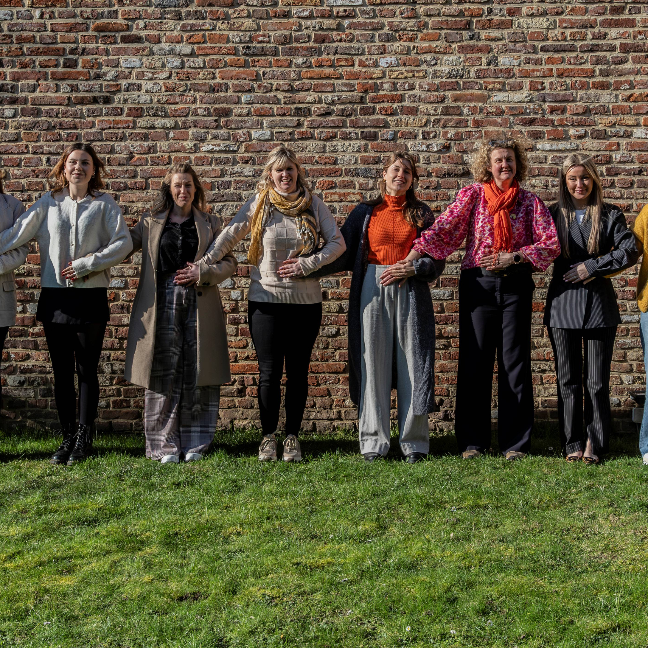 we zien 10 vrouwen die hun hand op elkaars onderbuik leggen